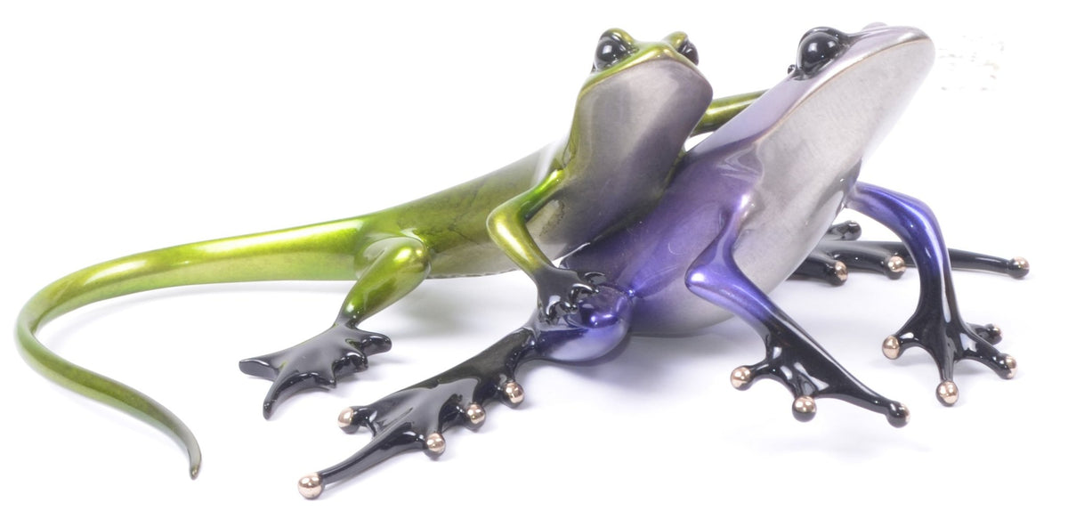 The glossy, stylized Sidekick sculptures by Tim Cotterill feature a green and purple frog with long legs and exaggerated feet. They sit closely together, reflecting light off their sleek surfaces against a plain white background.