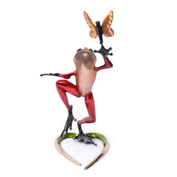 The Be Mine sculpture, a vibrant Frogman creation, showcases a colorful frog with a predominantly red body and black extremities reaching for an orange butterfly, perched on a green and beige base.