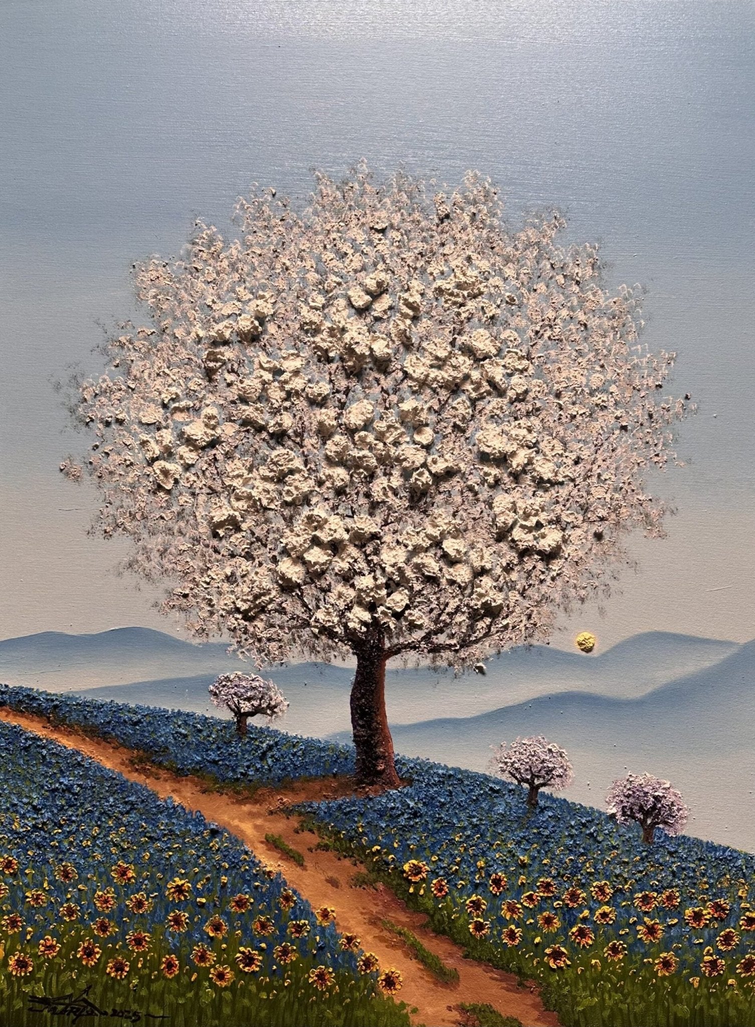 Blue Haze, an oil on canvas masterpiece by Mario Jung, features a white-blossomed tree on a hill with blue and yellow flowers, a winding path, three smaller flowering trees beneath a light blue sky, and soft hills.