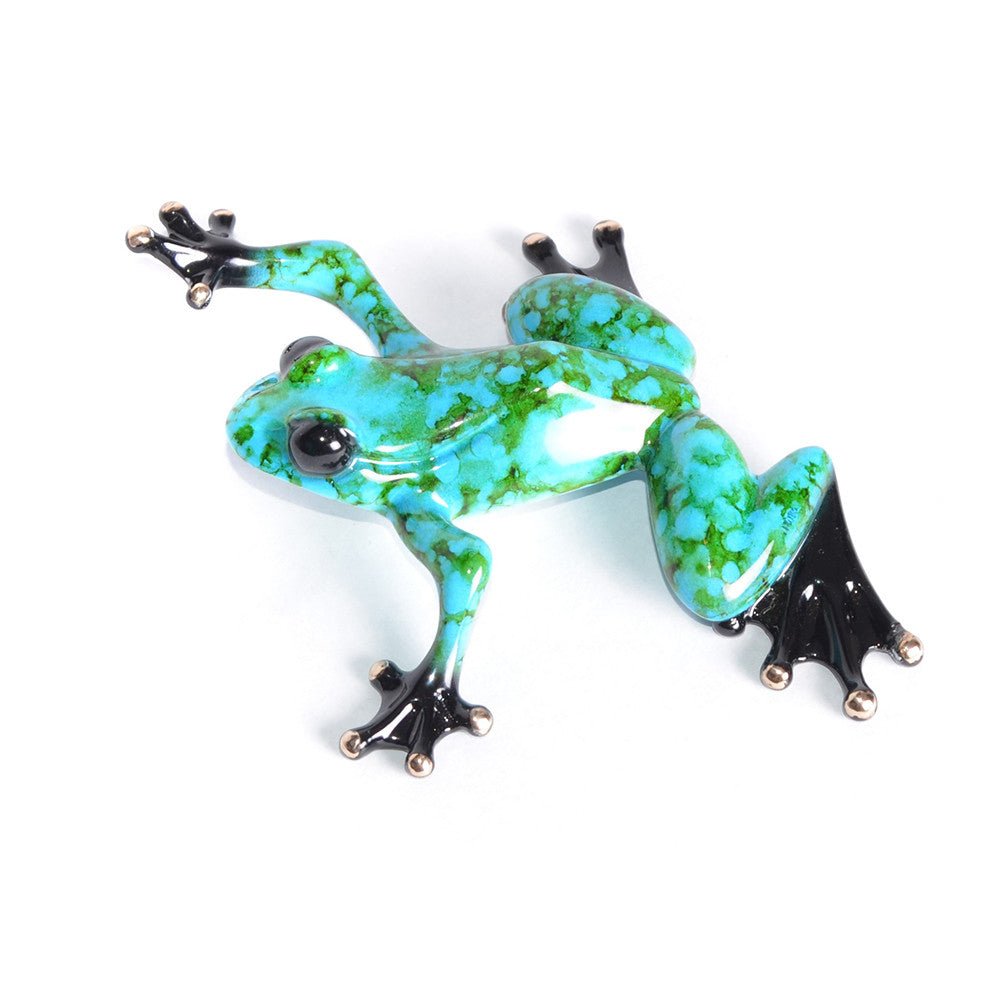 The ceramic sculpture Chase by Tim Cotterill showcases vibrant turquoise with black speckles. Its glossy finish highlights shiny dark toes and eyes contrasting against the white background, capturing Frogmans whimsical nature essence.
