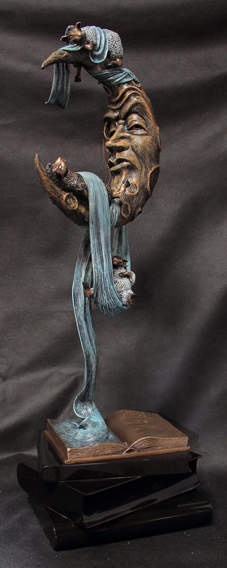 The surreal bronze sculpture, Counting Sheep, features a crescent moon face and flowing blue elements with mystical creatures dancing atop an open book-like base, evoking bedtime rituals and blending fantasy with dreamlike themes.