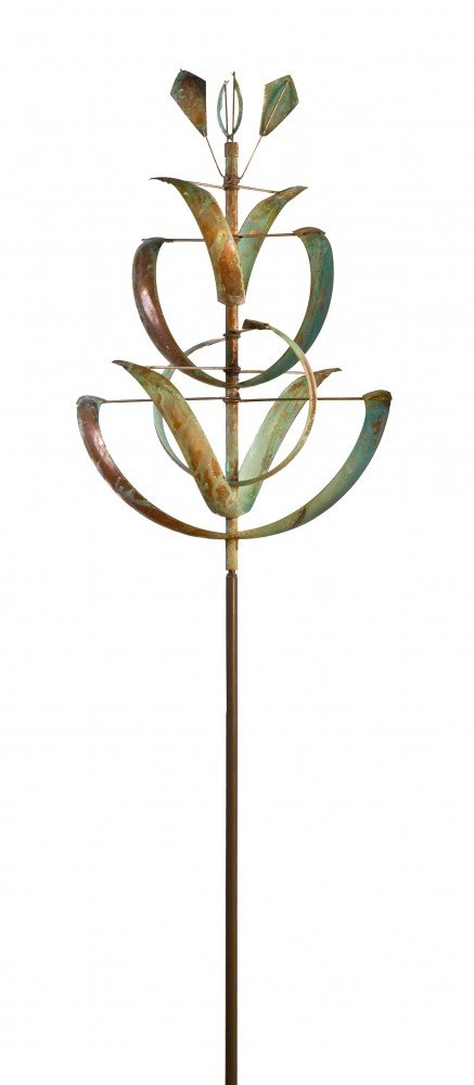 The Desert Lily is a Lyman Whitaker copper wind sculpture with layered, curved petals and arms on a vertical pole. It resembles a stylized Desert Lily sculpture, featuring elegant symmetry and a patina finish.