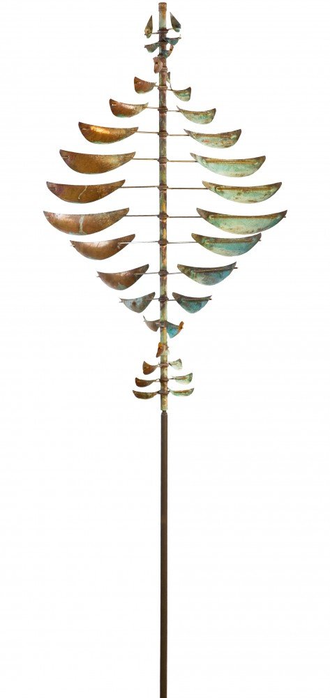 The Double Helix Sail by Lyman Whitaker is a kinetic sculpture with metal elements like leaves or fins, symmetrically around a central rod. Its patina blends green and bronze tones, evoking the natural beauty of Lake Tahoe.