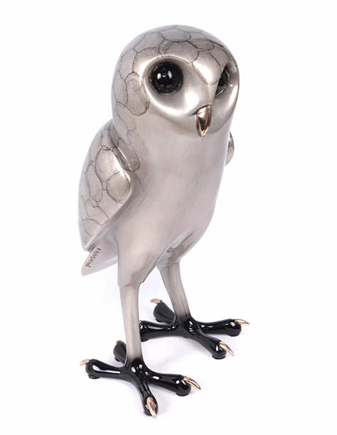 The Flaco Bronze Sculpture is a stylized owl crafted from metallic materials, featuring large glossy eyes, textured body patterns, and shiny black legs. Standing upright with a smooth appearance, this sophisticated bronze piece exudes elegance.