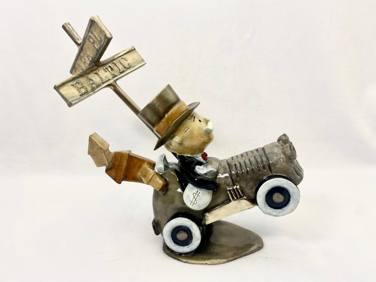 Paul B. Lotzs whimsical bronze sculpture, Highway to Hell, depicts a character in a suit and top hat driving a vintage-style car with rocket-like exhaust and a wooden signpost displaying Boardwalk and Baltic behind it.