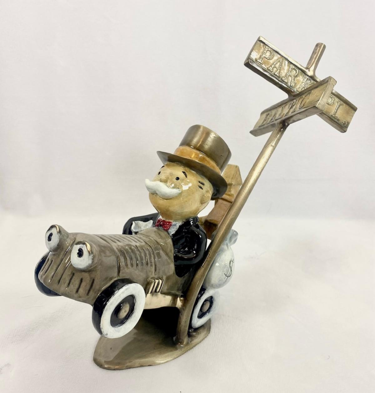 The Highway To Hell figurine by Paul B. Lotz depicts a cartoonish character with a mustache, top hat, and suit in an antique car. It has a glossy finish, Park and Place signs at the rear, evoking the playful style of a whimsical bronze sculptor.