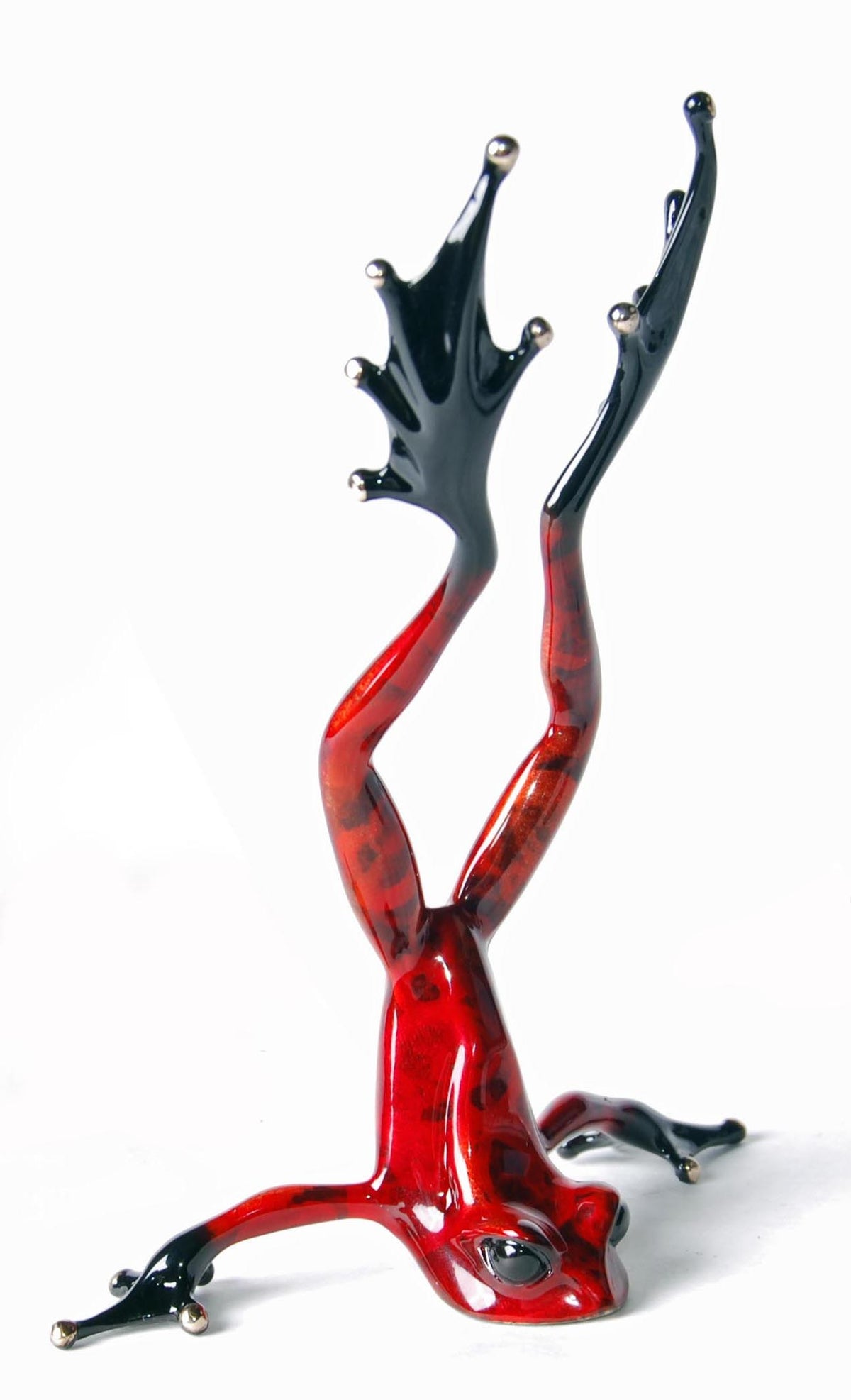 The striking Head Over Heels Frogman sculpture by Tim Cotterill features a vivid frog in a handstand with a glossy red body adorned with black spots and elegant black legs, perfectly capturing the dynamic spirit of bronze art against a white background.