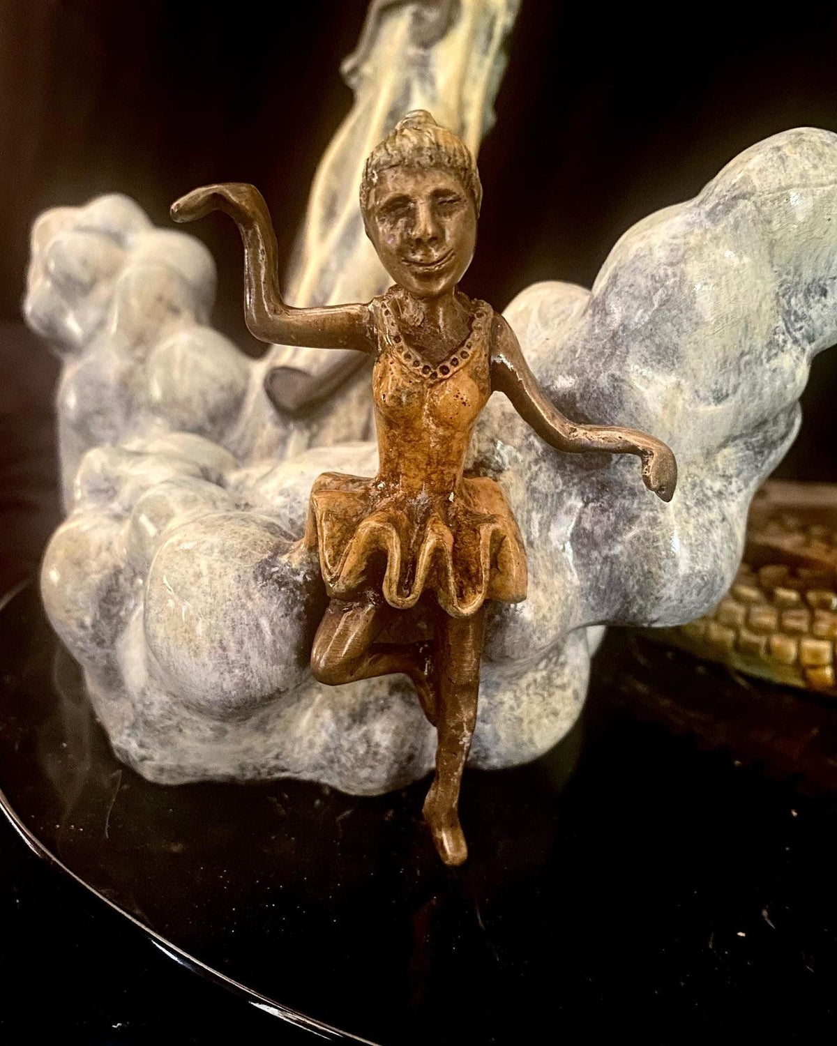 The sculpture If I Was a Sculptor features a bronze dancing girl in a tutu, gracefully posed on one leg with an elegantly raised arm against an abstract background reminiscent of Elton Johns Rocket Man, merging grace and fantasy with its cloud-like atmosphere.