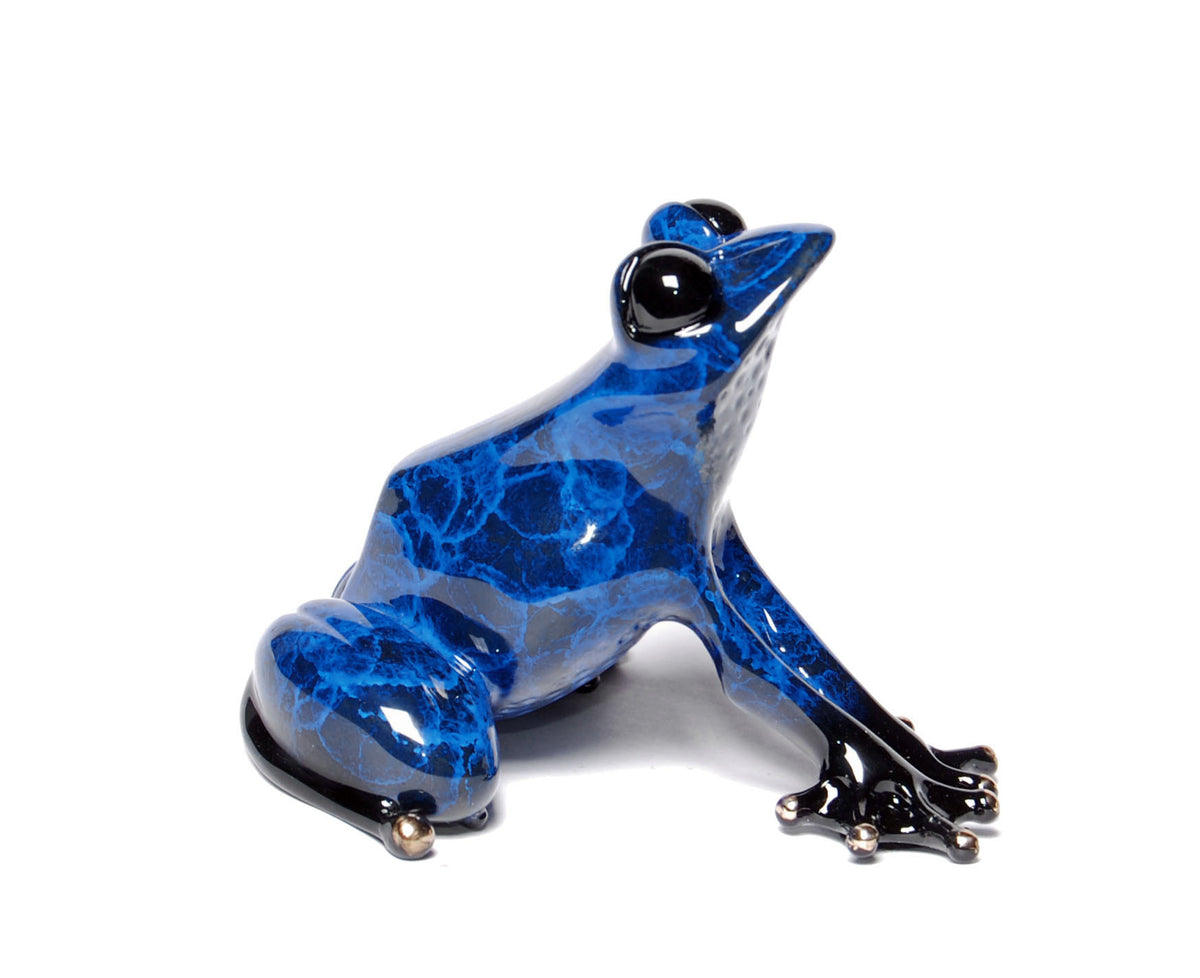 Indigo, a blue and black marbled frog sculpture by Tim Cotterill, features shiny black eyes and gracefully extended front legs as it faces right against a pristine white background.