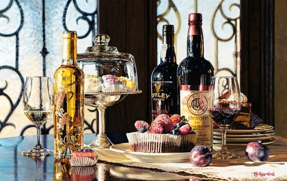 A La Dolce Vita table setting features decadent dark chocolate cake, cupcakes, and pastries under glass. Wine bottles and dessert wine enhance the scene as ornate iron window grills softly highlight a decorative golden tray in the background.