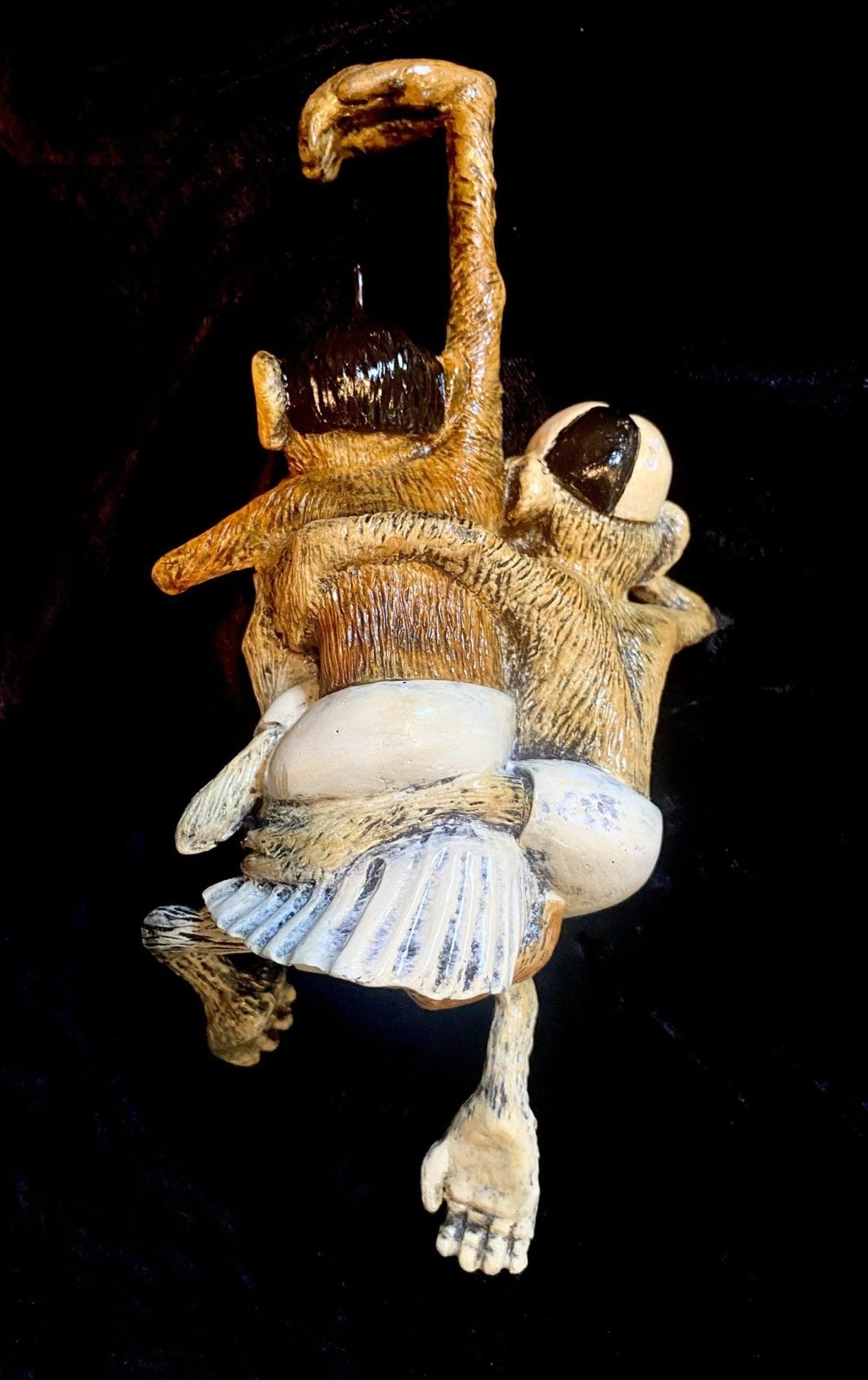 Paul Lotzs Little Rascals sculpture showcases two sloths intricately carved with rich fur textures, arms and legs intertwined, set against a dark background, capturing their playful charm.