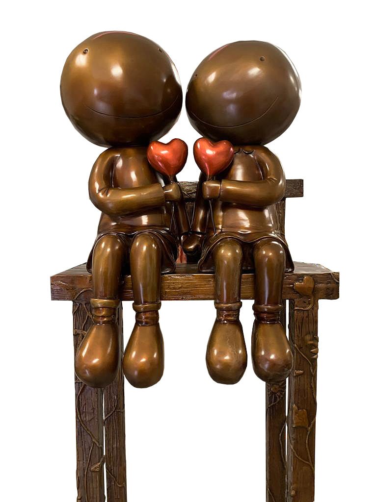 Lovers on the Bench features two bronze children with smooth, featureless faces seated together on a wooden bench, each holding a red heart—an evocative sculpture available at Marcus Ashley Gallery, reminiscent of Mackenzie Thorpes style.