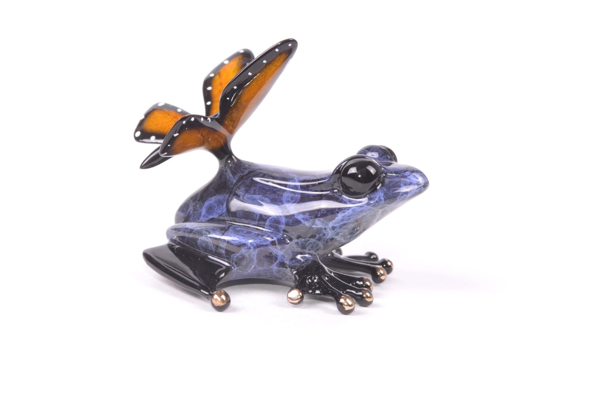 The Mariposa is a small, glossy Frogman sculpture with large eyes and whimsical butterfly wings with an orange interior and black edges. It features a marble-like purple pattern, and its feet have gold-tipped toes, making it a captivating piece of nature-themed decor.