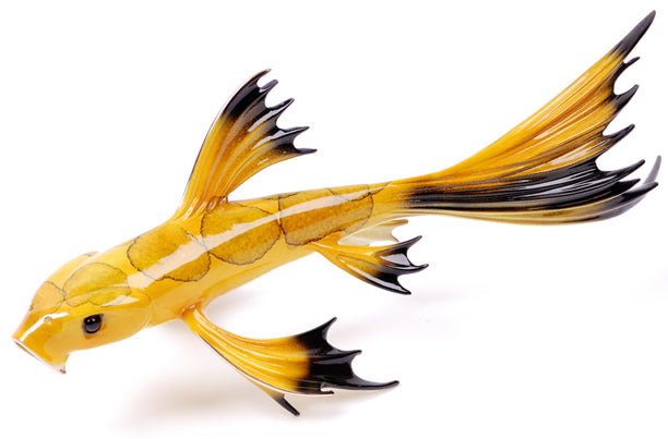 Mellow Yellow is a glass sculpture of a yellow fish with elongated fins and a black-tipped tail, shown against a white background.