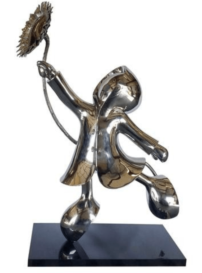 The My Sunshine-Stainless by Mackenzie Thorpe is a shiny stainless steel sculpture featuring a joyful figure in a hooded coat holding a sunflower. With its rounded limbs and black base, this limited edition piece radiates playful whimsy.