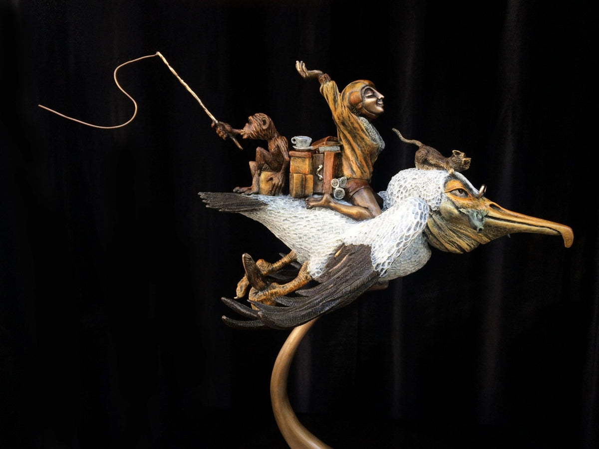 The whimsical bronze sculpture Ode To Amelia Earhart showcases a human-like figure, two monkeys, and various items riding on a large bird. The lead monkey holds a fishing rod, embodying adventure. Against a dark background, its intricate details and vibrant colors come to life.