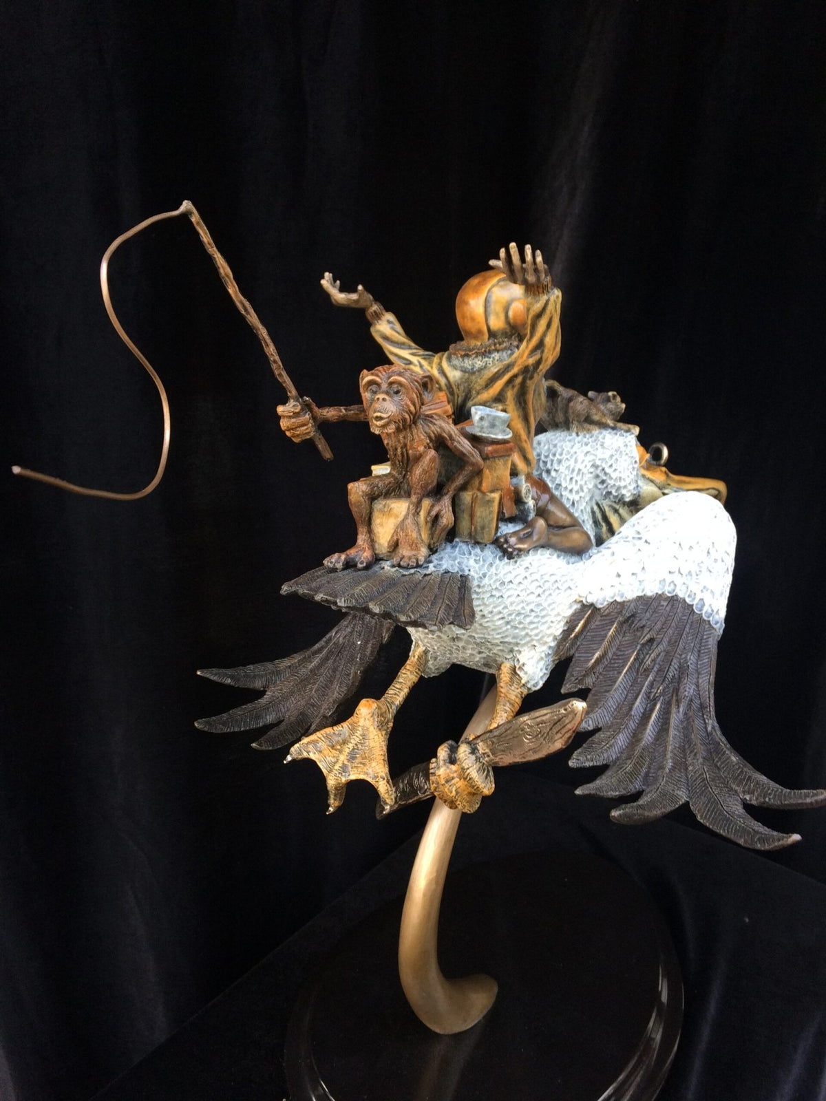 Ode To Amelia Earhart is a whimsical bronze sculpture featuring a monkey with a bent-stick riding an oversized bird. Its textured wings and detailed feet stand out against a black background, capturing the adventurous essence of Amelia Earharts daring voyages.