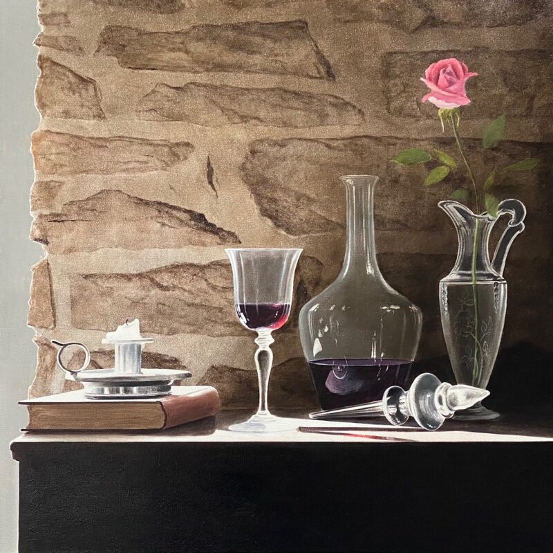 Still Life with Single Rose echoes Alexander Volkovs art, featuring a book, candle holder, wine glass, decanter, and pink rose vase on a dark surface against a textured stone wall—capturing the sophisticated charm often seen at Marcus Ashley Gallery.