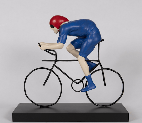 The limited edition bronze sculpture The Fastest by Mackenzie Thorpe depicts a cyclist in a blue suit with a red helmet on a sleek black bicycle atop a black base, capturing the dynamic form reminiscent of the Tour de Yorkshire.