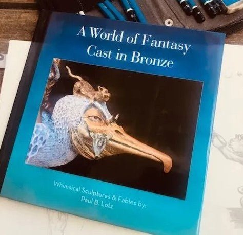 The image displays the World of Fantasy Cast in Bronze Book, an enchanting fantasy art book by Paul B. Lotz, featuring a cover with a bronze sculpture of a whimsical creature with a long beak and a small animal perched on its head.