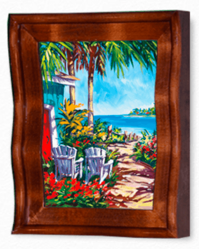 A framed painting titled Cinnamon Bay shows a tropical scene with two white chairs on the shore, surrounded by palm trees and vibrant flowers. A clear blue sky and distant land complete this quintessential Steve Barton Art piece.
