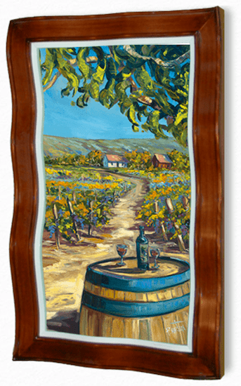 A framed painting, echoing Steve Barton’s style, depicts a Vineyard Vines scene with a vineyard, winding path, wine barrel table with a wine bottle and glasses in the foreground, and rolling hills with a house under a blue sky in the background.