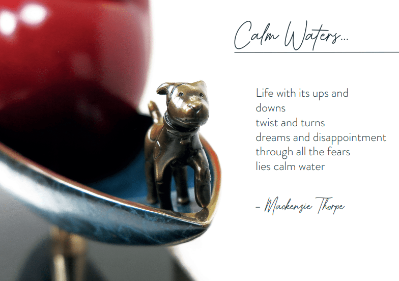 A small metal dog sculpture at the boats prow epitomizes Mackenzie Thorpe art. The artwork, Calm Waters, features artistic text: Life’s ups and downs, twists and turns, dreams and disappointment; through all fears lies calm water - Mackenzie Thorpe.