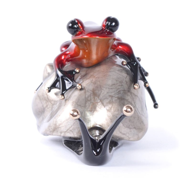 The EsCargo sculpture features a red and black frog reminiscent of Frogman art, perched on a polished metallic rock. Its glossy texture and intricate details reflect light, highlighting vivid colors and a smooth surface like pieces at Marcus Ashley Gallery near Lake Tahoe.