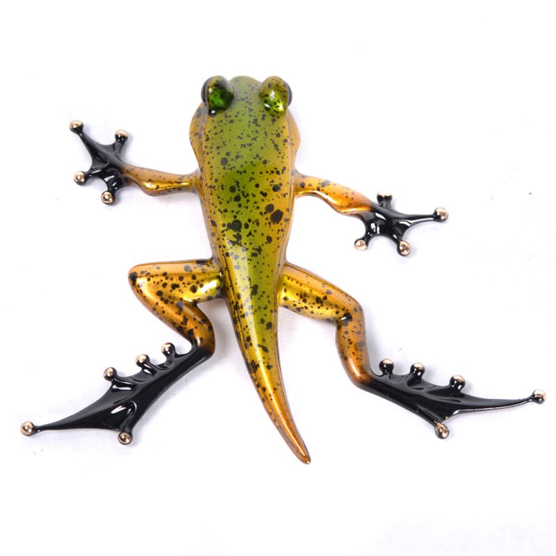 The Froglet sculpture by Frogman art features a glossy gold and green body with black speckles against a white background. Its elongated limbs and webbed toes showcase the elegance typical of Tim Cotterills designs.