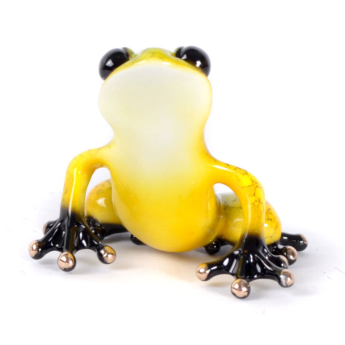 The small, glossy yellow Salsa glass frog figurine with black feet and bold black eyes, resembling Tim Cotterills Frogman art style, sits upright on a white surface.