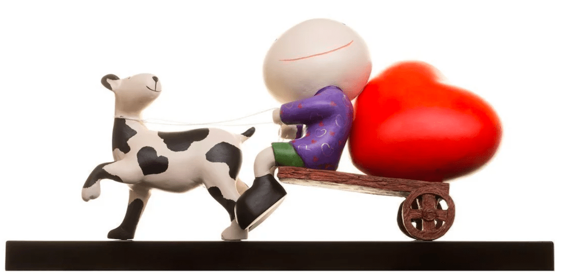 Happy Days is a whimsical Mackenzie Thorpe limited edition figurine featuring a character with an oversized round head in a purple outfit on a wooden cart with a red heart, pulled by a black and white cow.