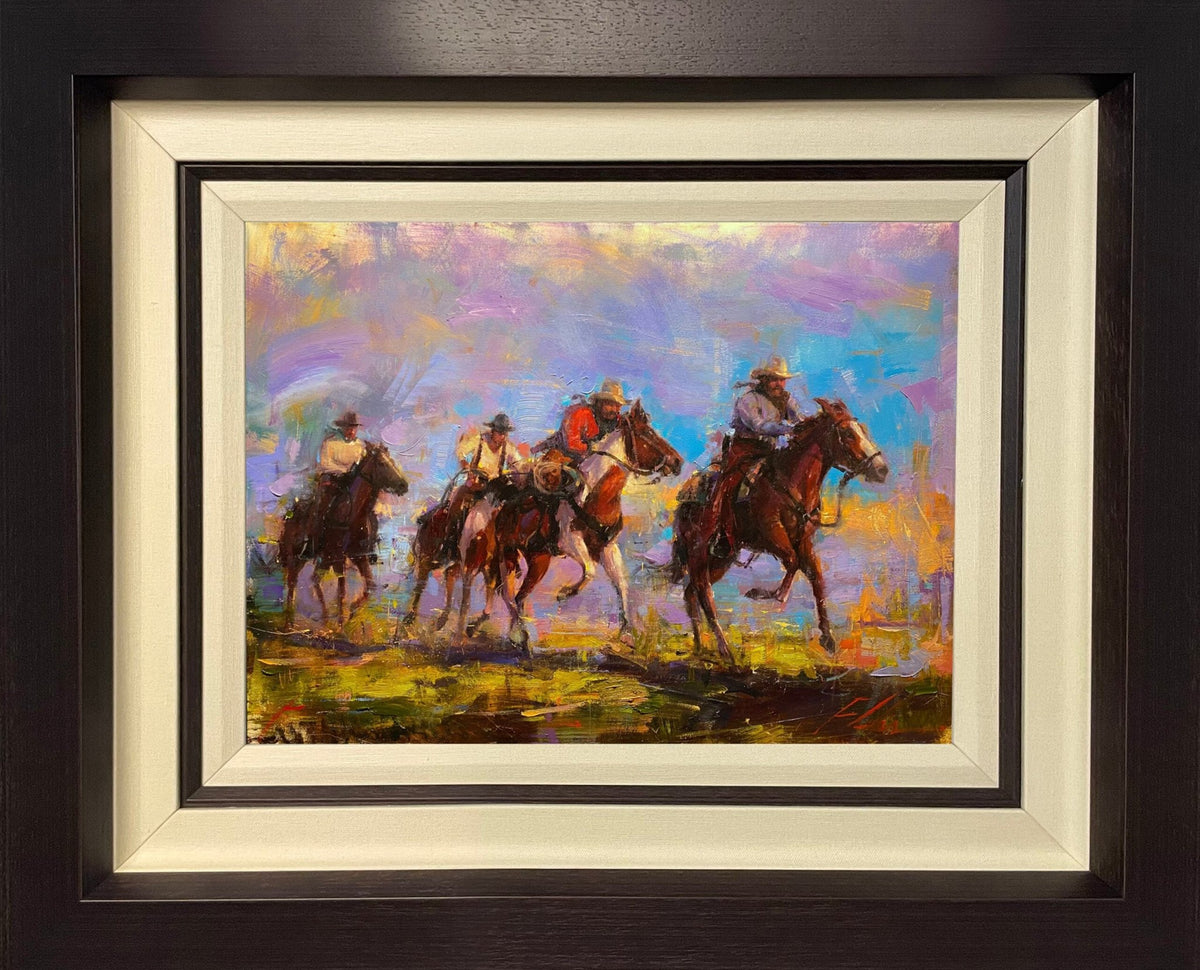 The framed painting Outlaws depicts four cowboys on horseback traversing a colorful, abstract landscape. It features vibrant hues of purple, orange, and blue in an impressionistic style.
