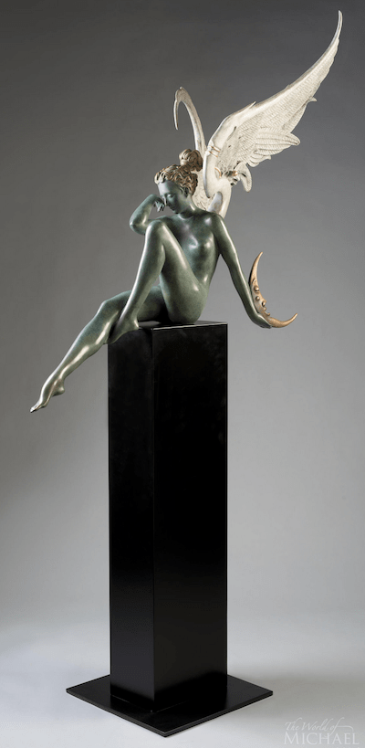 The Moonstruck sculpture, akin to a Michael Parkes piece, depicts an angelic figure on a tall black pedestal with metallic green patina and detailed white wings. The figures relaxed pose features one hand on the chin, with a crescent shape subtly at the base.