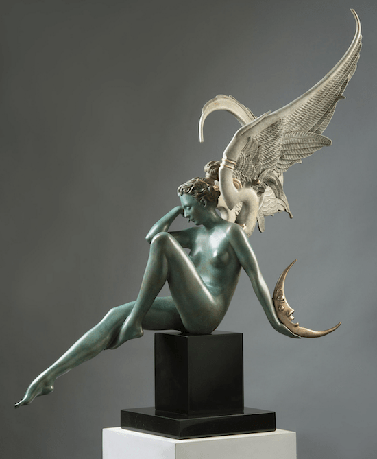 The Moonstruck sculpture by Michael Parkes features a winged, semi-nude figure seated on a pedestal. A detailed metallic wing unfurls as the figure cradles a crescent moon, bathed in green patina and bronze hues, striking a contemplative pose against the gray backdrop.