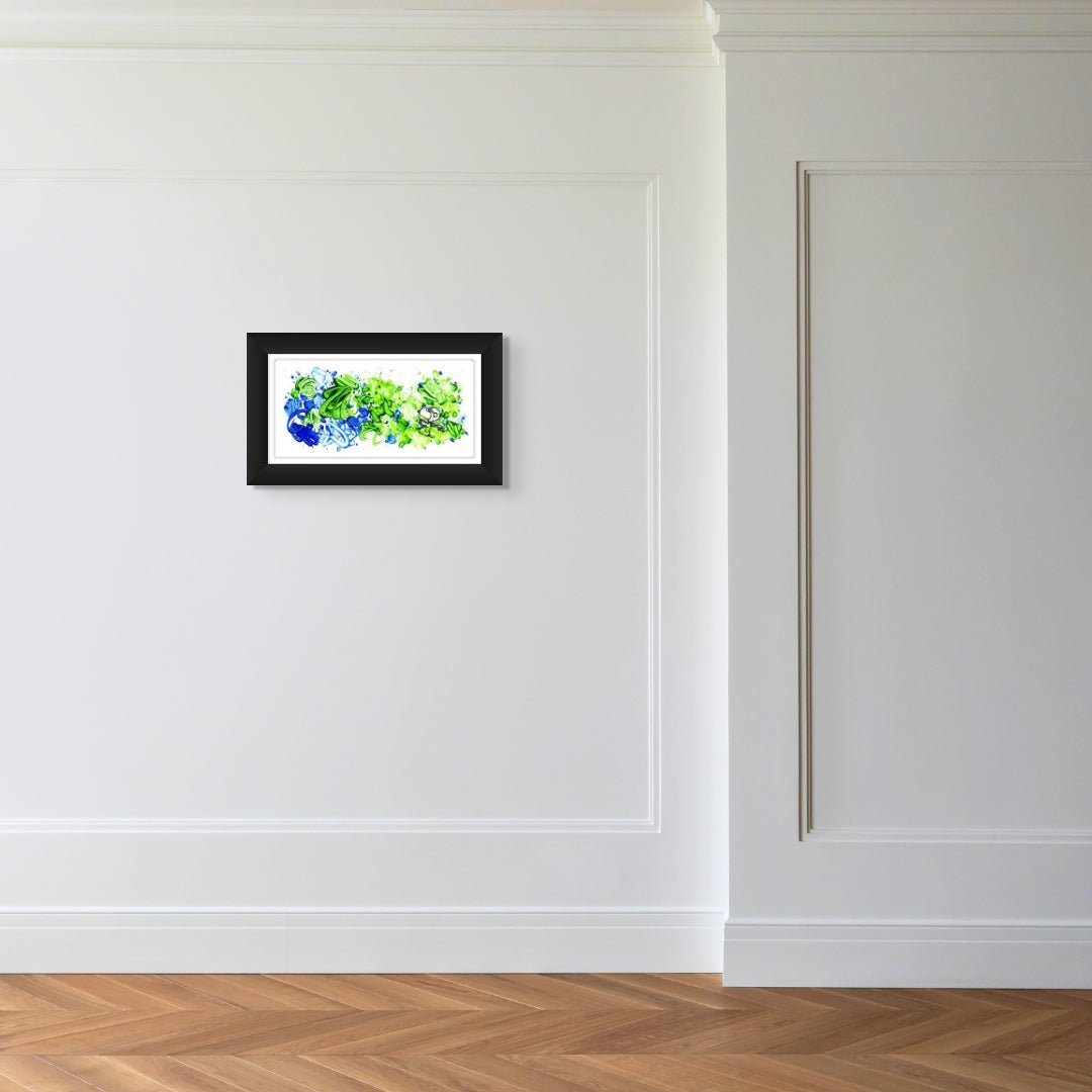 A minimalist room with white paneled walls and wooden herringbone flooring showcases whimsical art. Centered on the wall is Partly Cloudy 6:15 Morning Fly, a small abstract painting in green and blue hues, framed in sleek black, reminiscent of Tom Everharts style.
