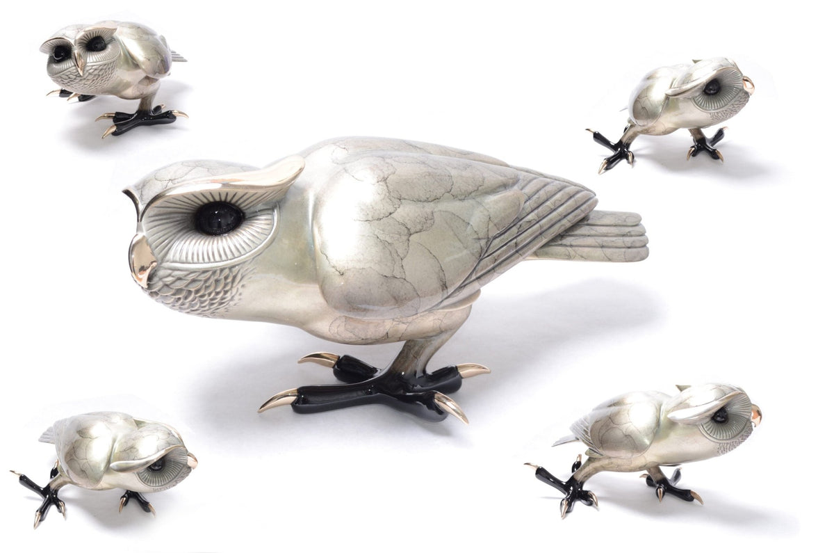 Five sculptures named Shakespeare, featuring silver stylized owls with intricate feather details and glossy black eyes, are displayed. These owl figures resemble bronze designs, vary in size, and are set against a white background to form an artistic and elegant scene.