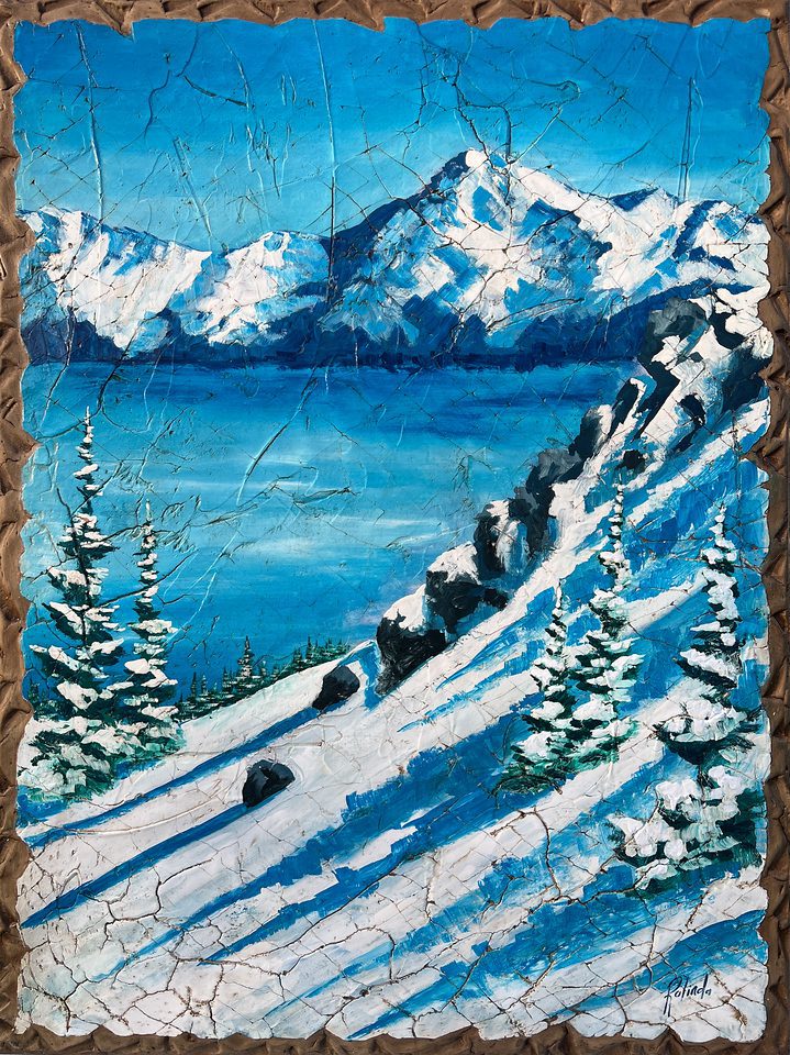 The textured painting Sliding Into Home Base depicts a snowy mountain landscape beneath a clear blue sky, with snow-covered pine trees and rocky slopes extending to distant mountains, all framed by a rustic wooden border that complements the winter scenery.