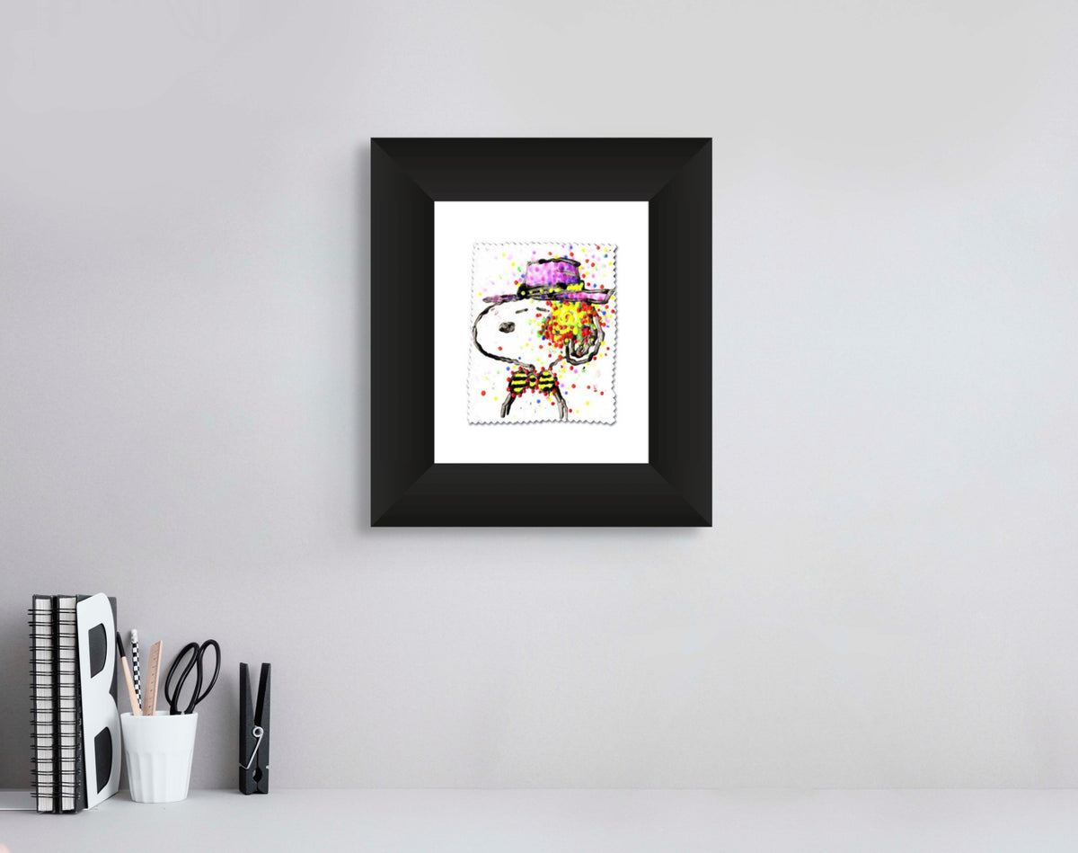 Tom Everharts framed Tahitian Hipster III artwork of a cartoon dog in a purple hat adorns a light gray wall. Below, a shelf displays books, a large letter B, and a container with scissors, pens, and a ruler, evoking island sophistication.