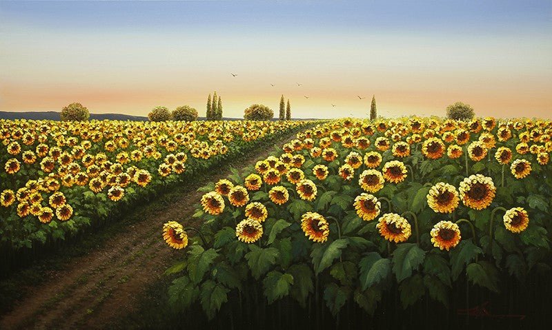 A vast sunflower field under a clear sunset sky echoes the essence of Mario Jungs Walking in the Sun. A dirt path weaves through sunflowers toward distant trees, while birds soar above, and warm light casts a golden glow on the scene.