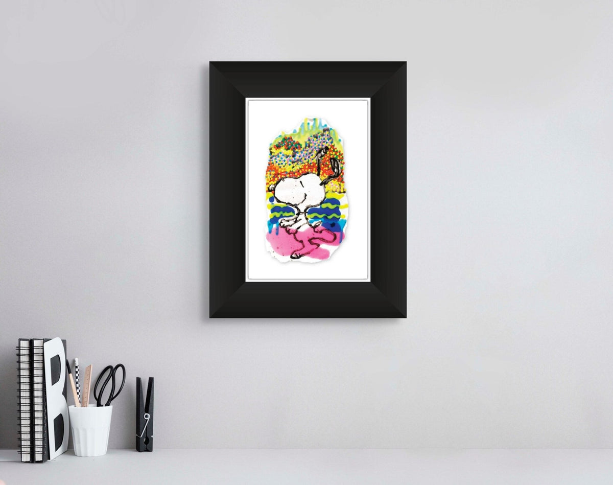 The framed Water Lilly II art piece, featuring playful colors, creates a lively contrast against the light gray wall. It elegantly hangs above a white desk adorned with books, a letter B, and a cup filled with pens and pencils, showcasing modern artistry.